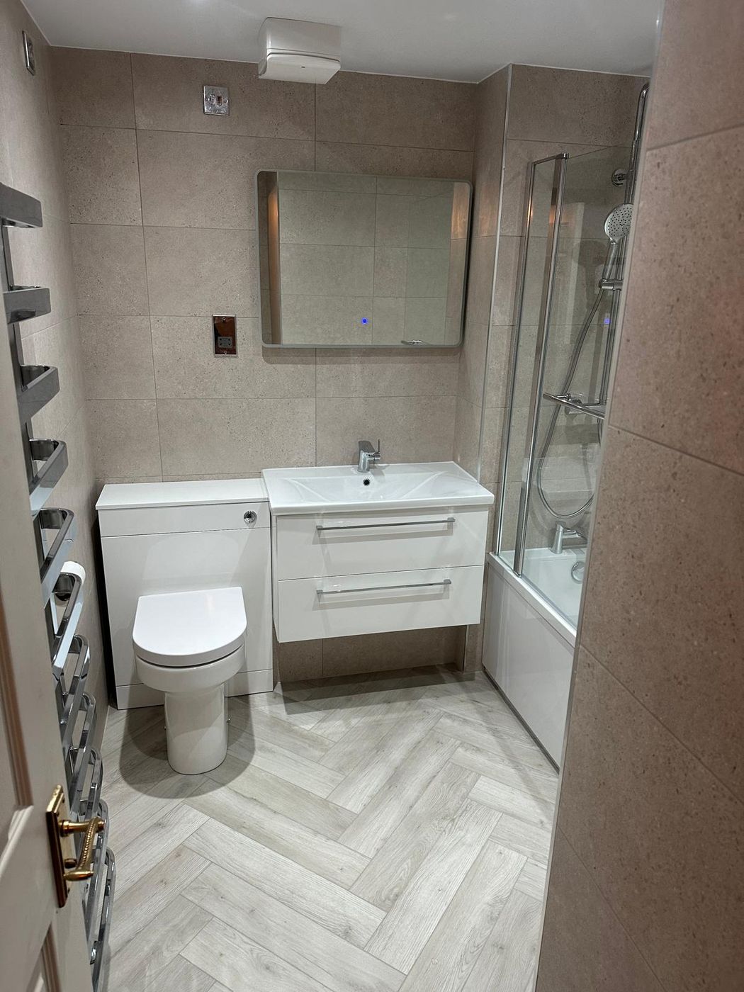 Refitted bathroom in Edinburgh with stone-effect wall tiling, herringbone flooring and a white vanity unit