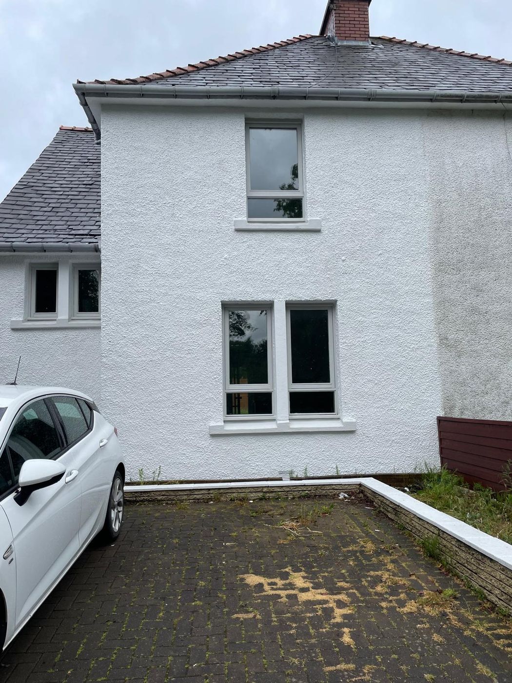 Exterior of a roughcast house repainted in white with fresh window surrounds