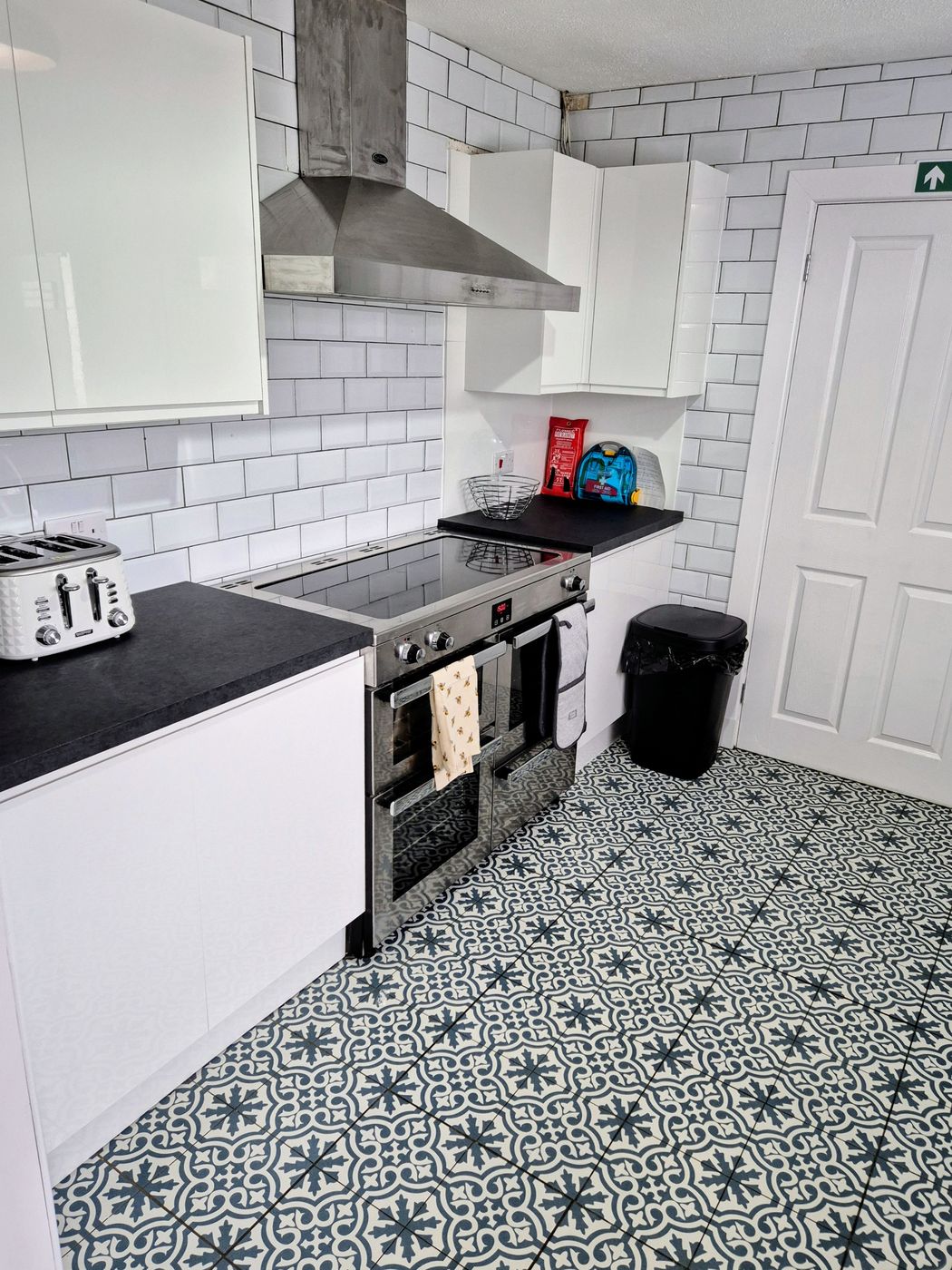 Fitted kitchen with gloss white units, dark worktops, metro tiling and patterned floor tiles